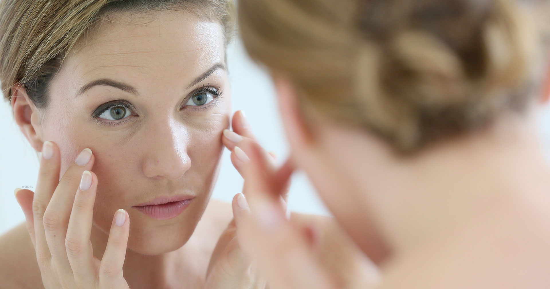 Woman looking at her face in the mirror