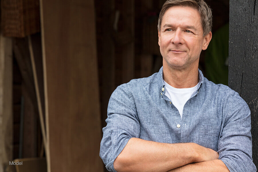 Attractive middle-aged man with crossed arms smiling as he looks off into the distance