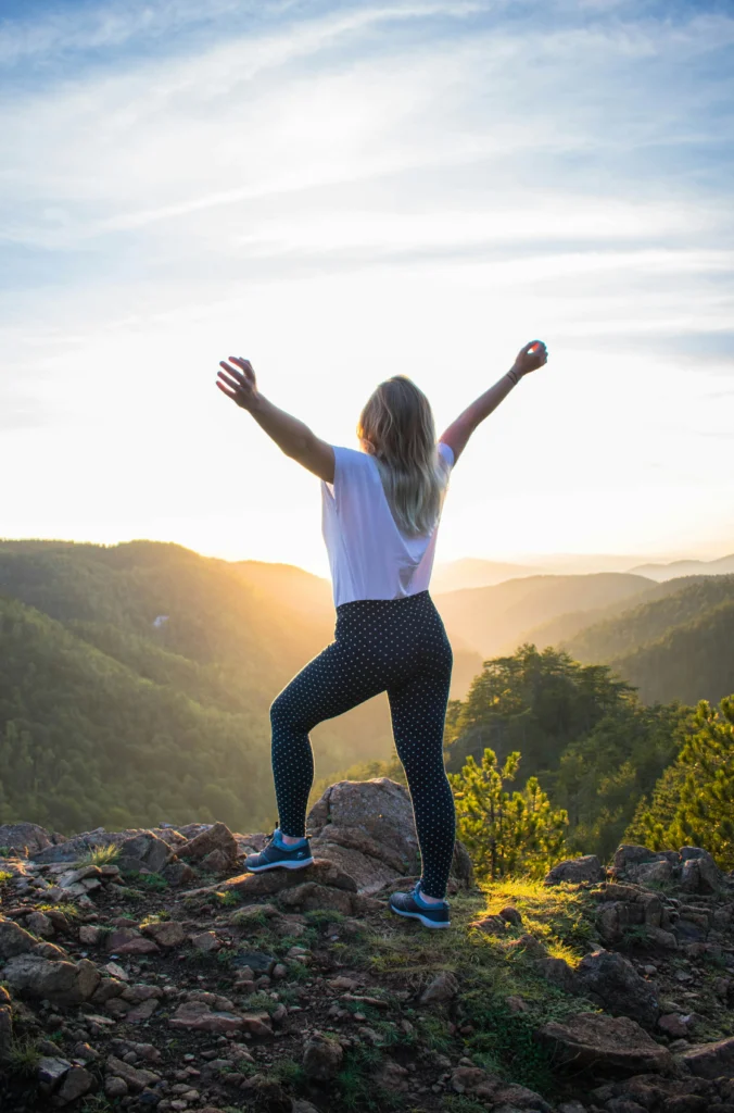 Image of a woman celebrating outdoors after understanding how long does it take for labiaplasty to heal and returning to activity