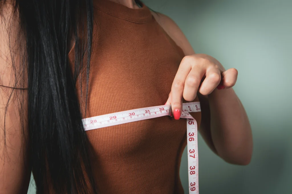 Image of a woman measuring her chest size with a tape measure around her bust