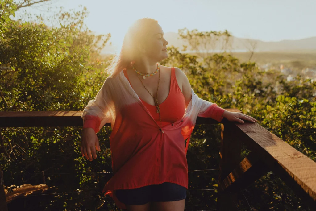 Image of a woman relaxing outdoors on a wooden deck at golden hour with lush greenery and mountains in the background