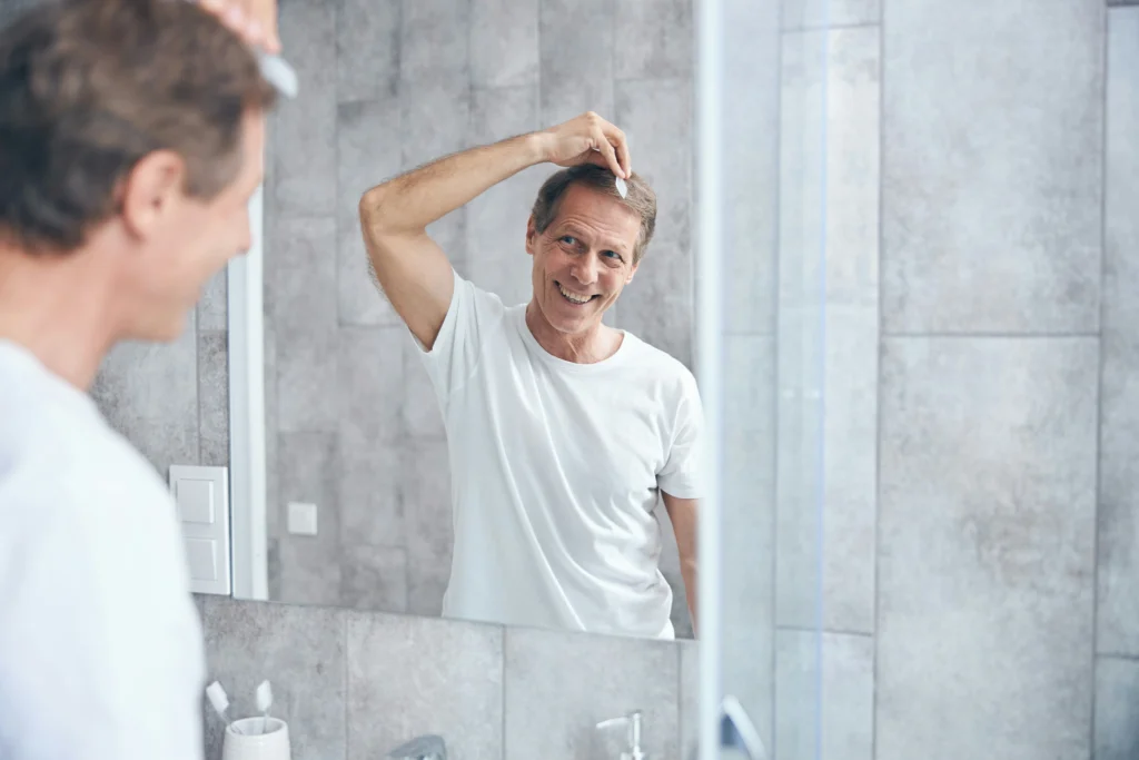 Image of a man checking his hair in a bathroom mirror during post operative hair transplant recovery progress