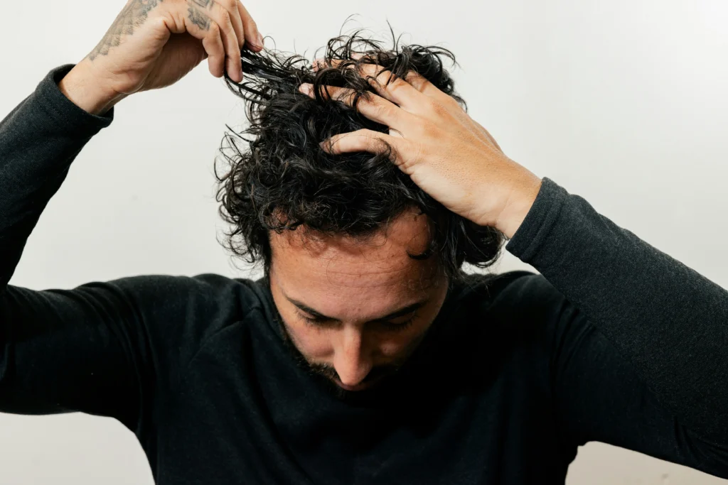 Image of a man with thick curly hair running his hands through it