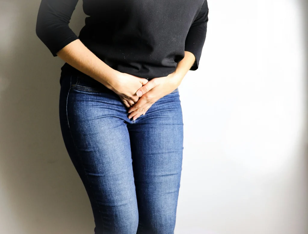 Image of a woman in jeans experiencing vaginal discomfort portraying why would someone get a labiaplasty