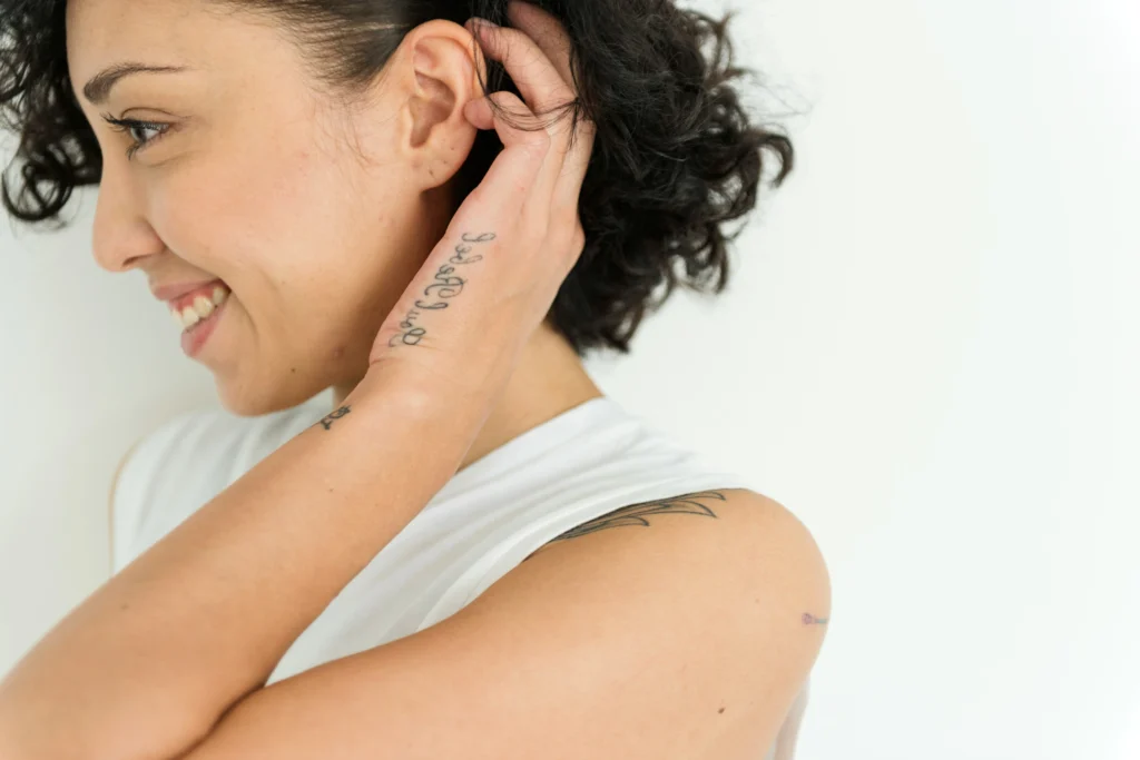 Image of smiling woman touching her ear after learning otoplasty cost