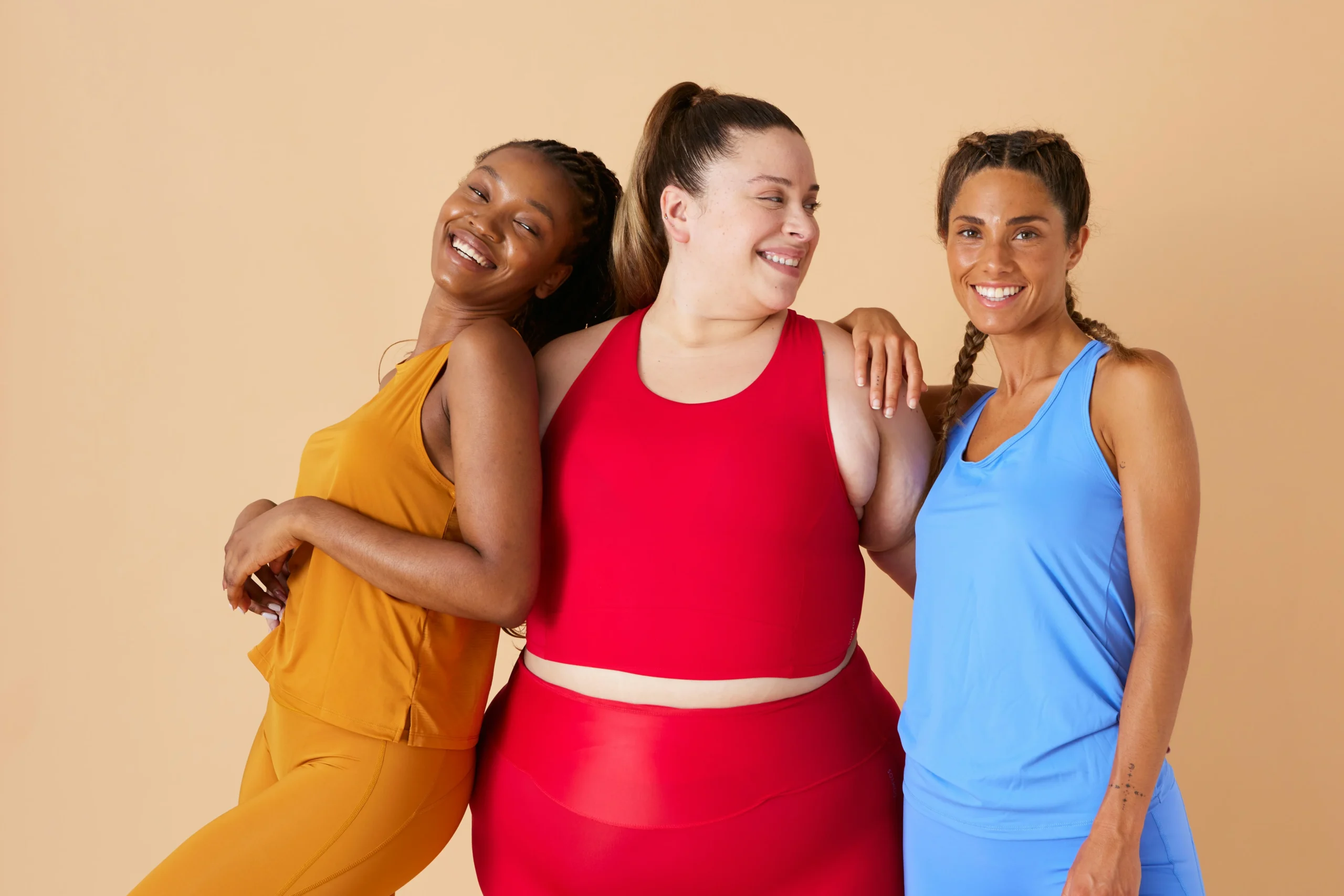 Image of three diverse women in athletic wear smiling together