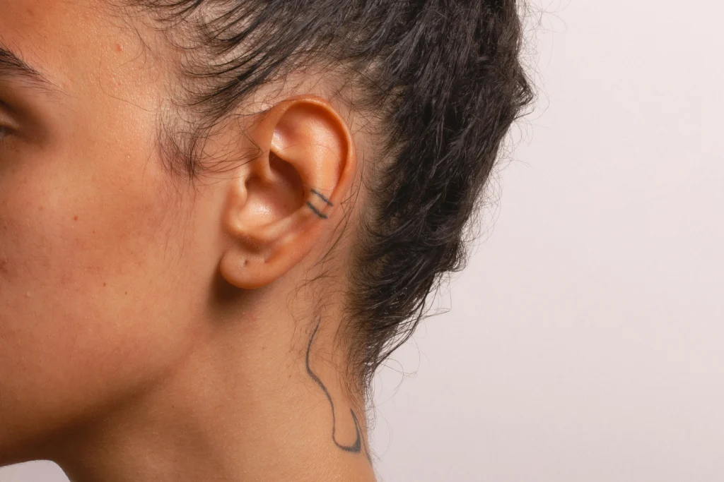 Image of woman's ear after otoplasty with small tattoo on helix