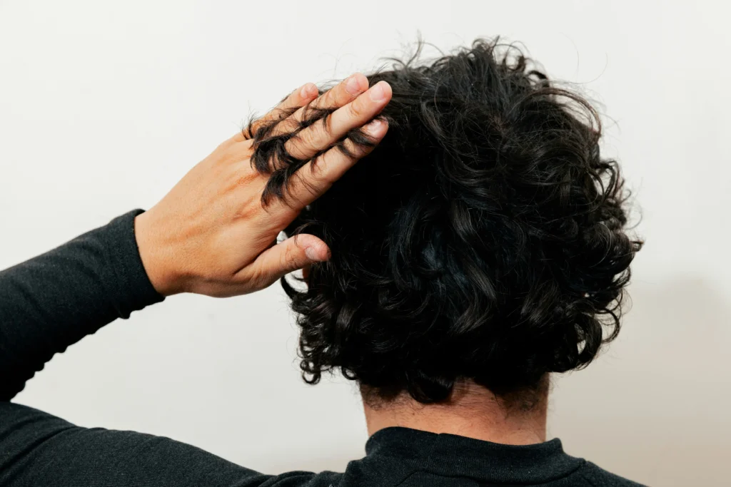 Image of man touching healthy hair on the back of his head